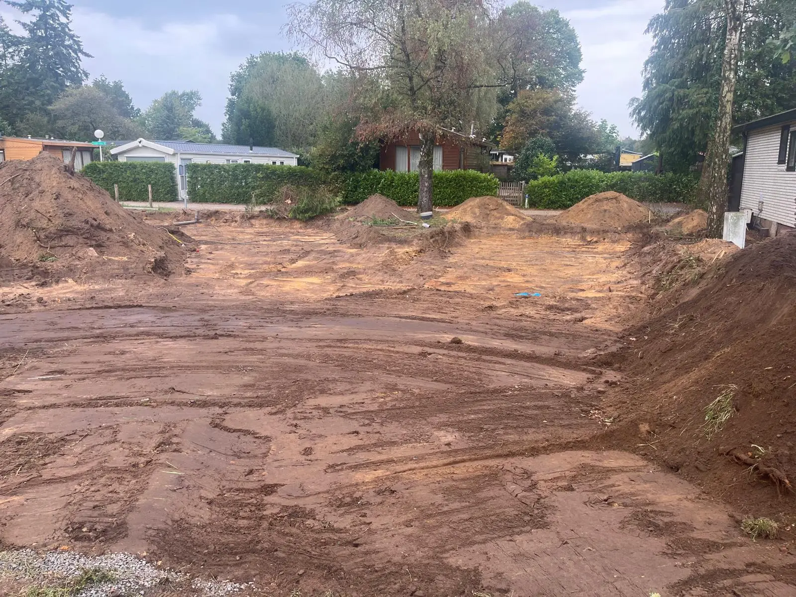 Overzicht van de uitgegraven kavels met grondhopen op een park in Putten, tussen bestaande chalets en bomen